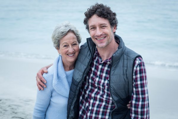 Happy mid adult man with elderly mother at sea shore