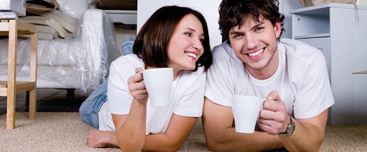 man and woman lying on floor with mugs smiling