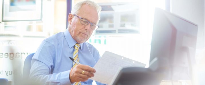 Man reads paper at work station