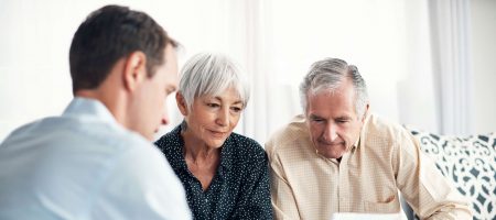 elderly couple and man holding paper sitting down