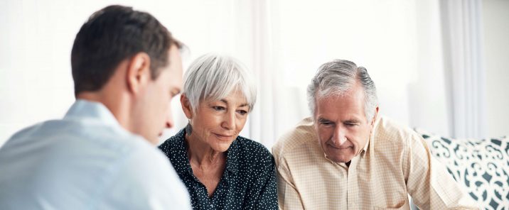 elderly couple and man holding paper sitting down