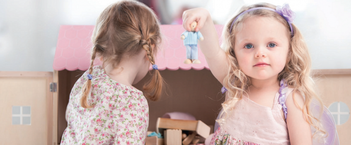 two girls children playing with doll house