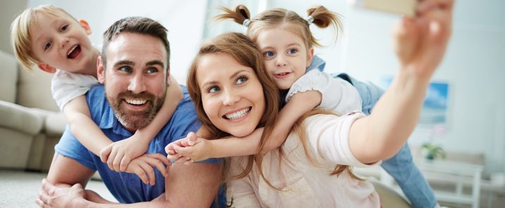 parents taking selfie with two young children on floor INVERSED