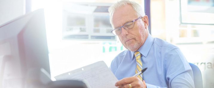 man in office at desk looking at paper