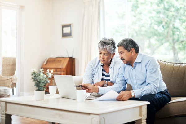 man and woman on sofa pointing at laptop