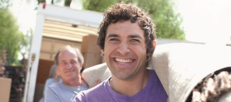 close up two men carrying rolled up carpet