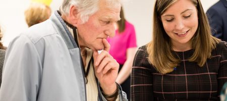 man holding chin looking at pamphlet held by woman