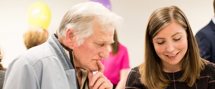 man holding chin looking at pamphlet held by woman