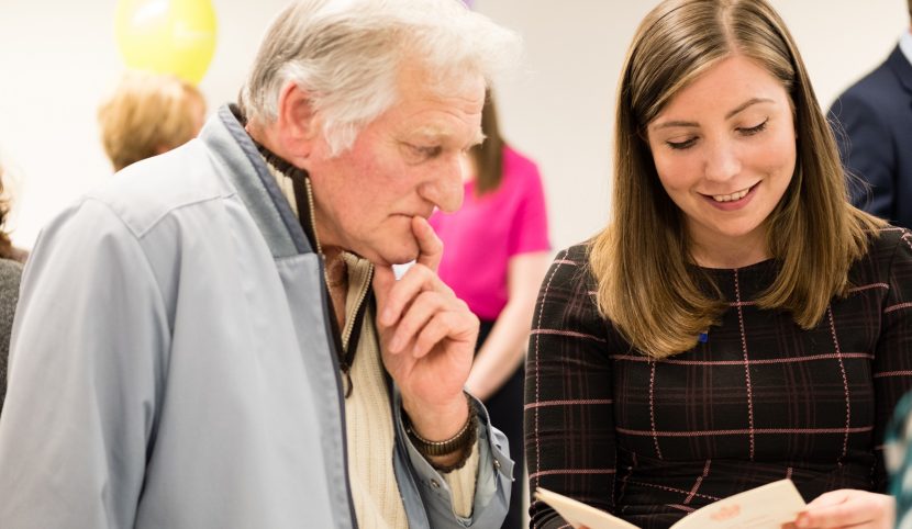 man holding chin looking at pamphlet held by woman