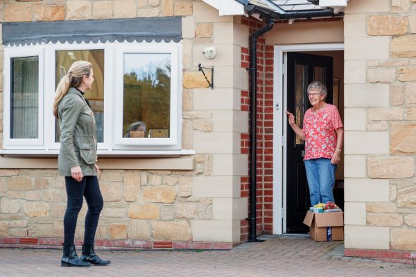 woman leaving other woman package at front door
