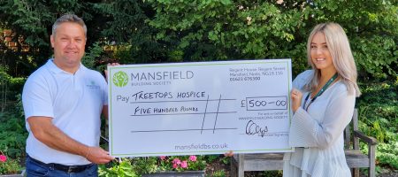Treetops hospice man and woman holding mansfield cheque outside