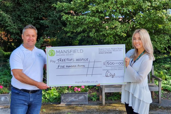 Treetops hospice man and woman holding mansfield cheque outside
