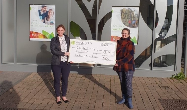 Two women holding mansfield cheque for schools out