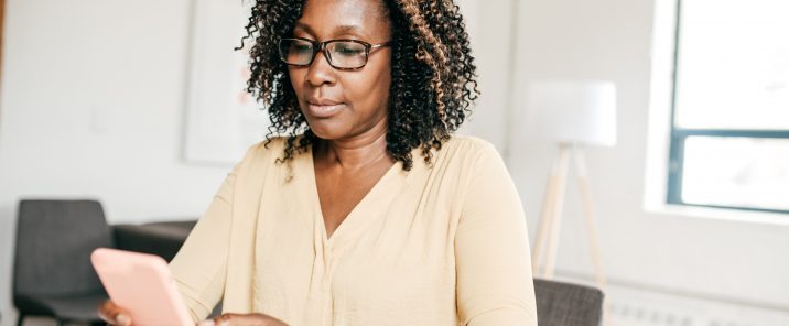 Woman looking at pink phone at desk