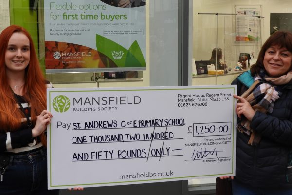 Two women holding mansfield bs cheque st andrews primary school