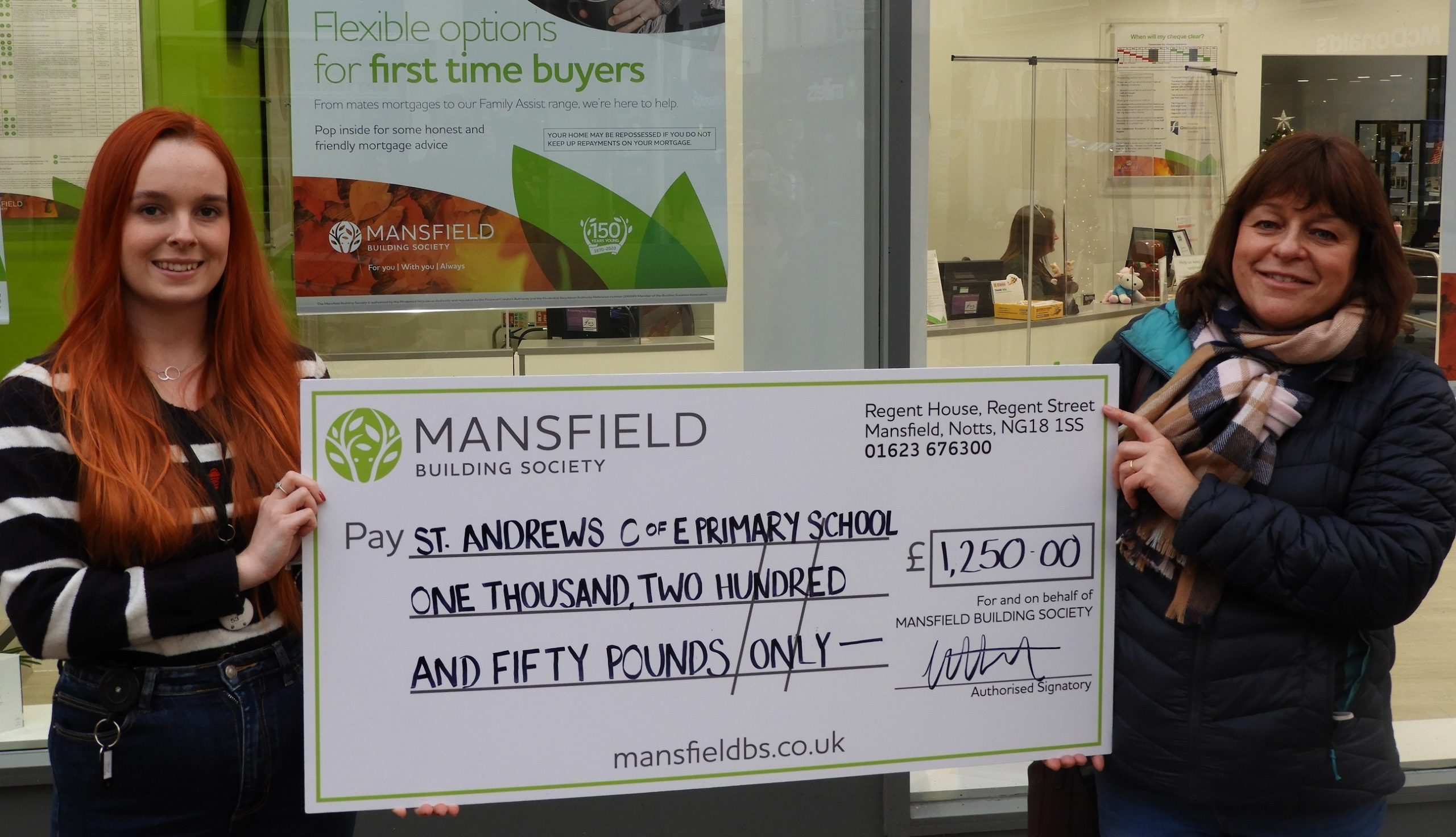 Two women holding mansfield bs cheque st andrews primary school