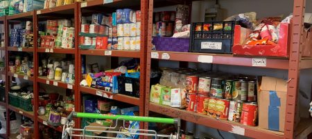 Foodbank shelves of food and shopping trolley