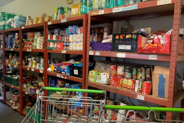 Foodbank shelves of food and shopping trolley