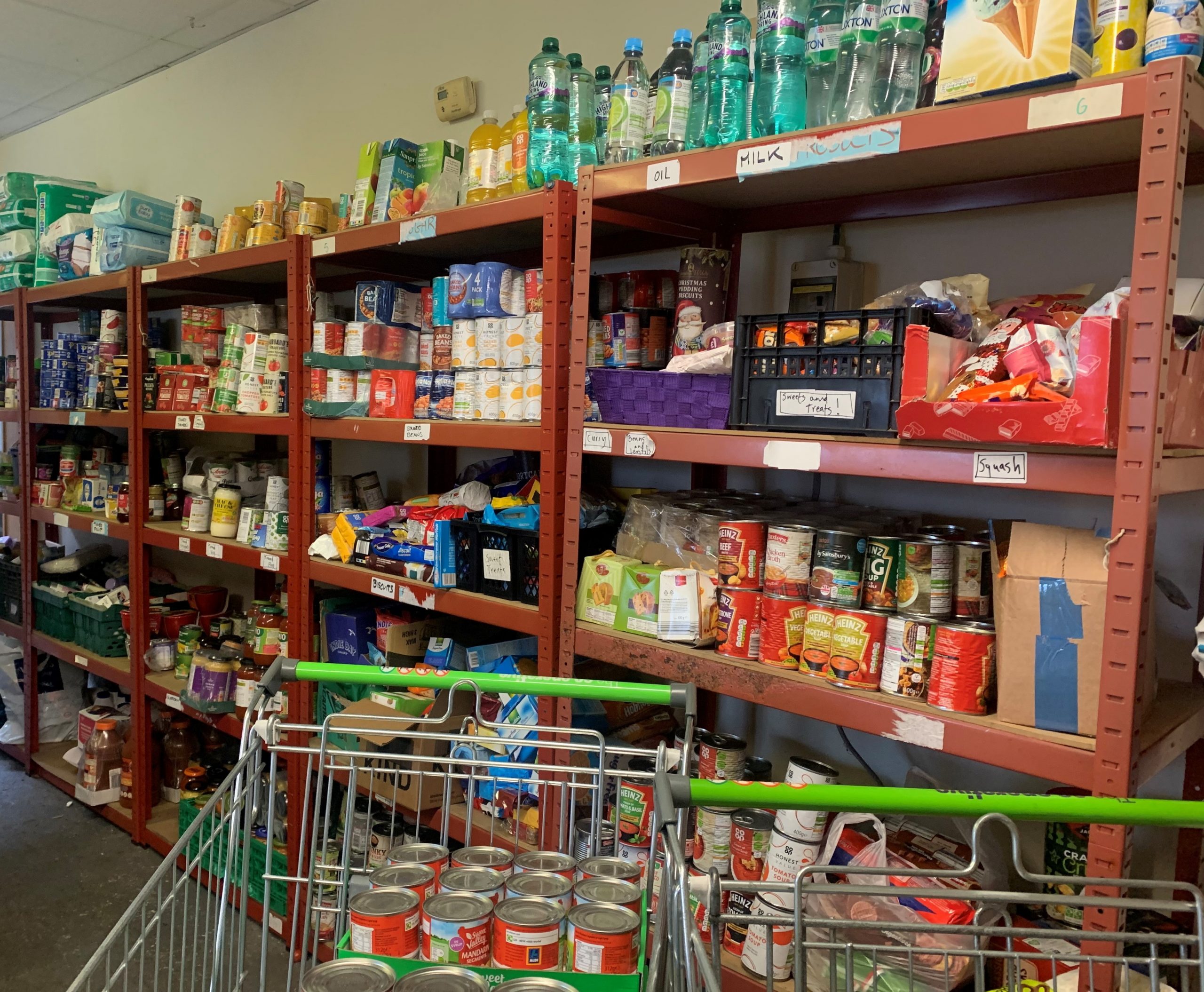Foodbank shelves of food and shopping trolley