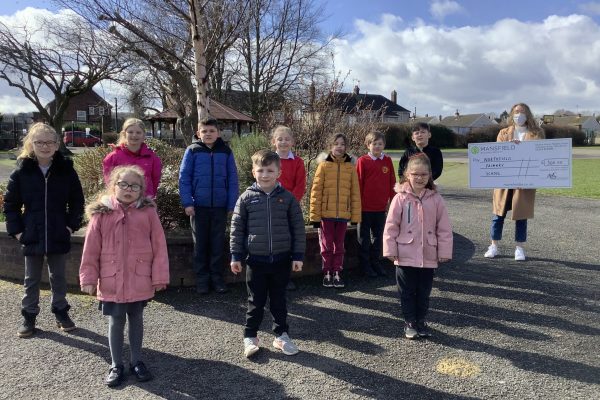 Children standing by tree woman holding mansfield bs cheque