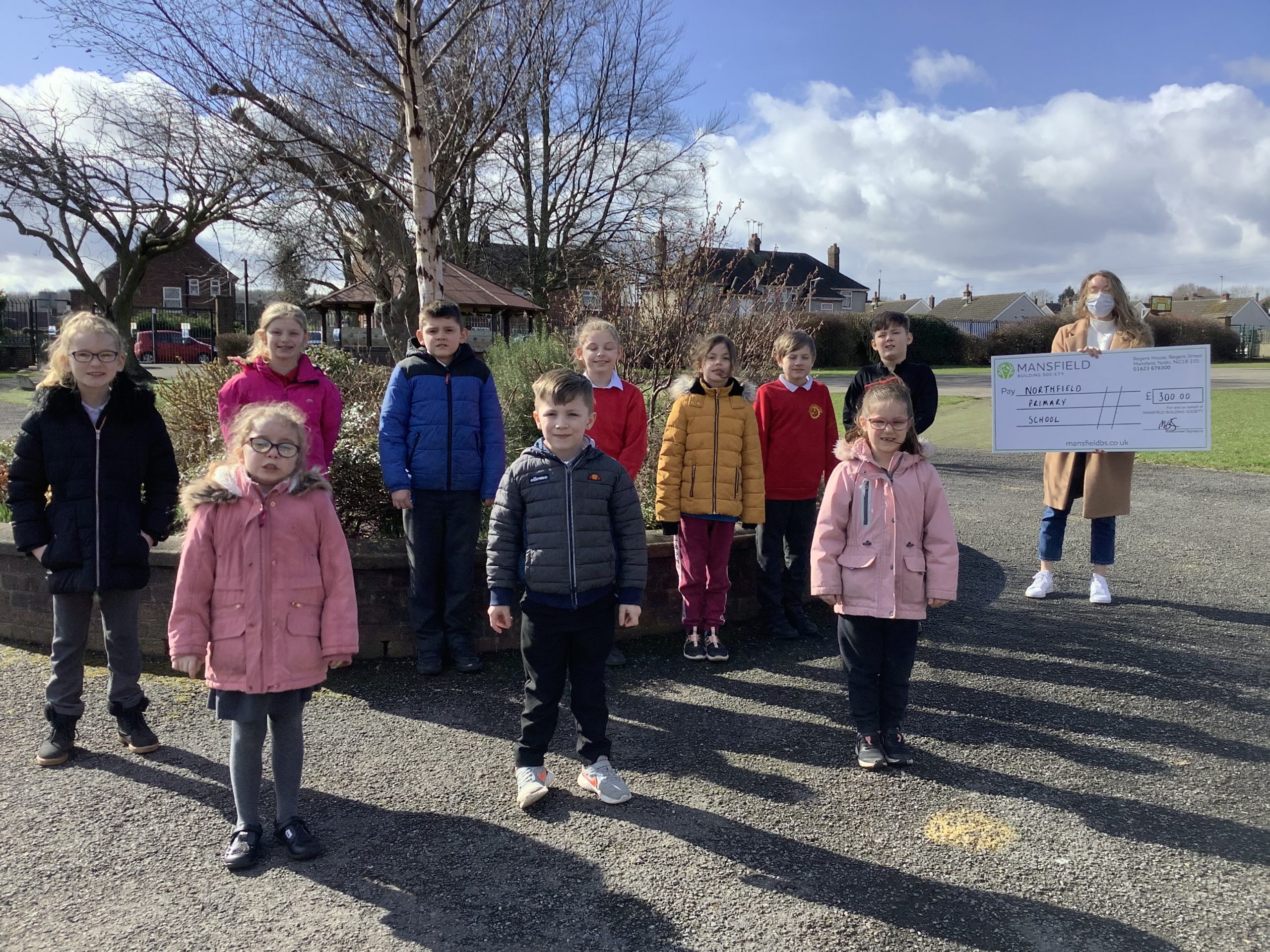 Children standing by tree woman holding mansfield bs cheque