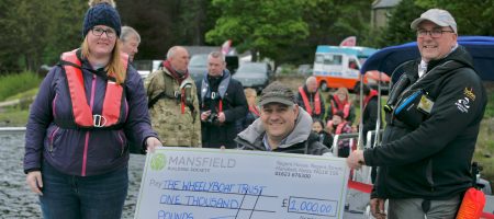 Man and woman and man in wheelchair holding mansfield bs cheque