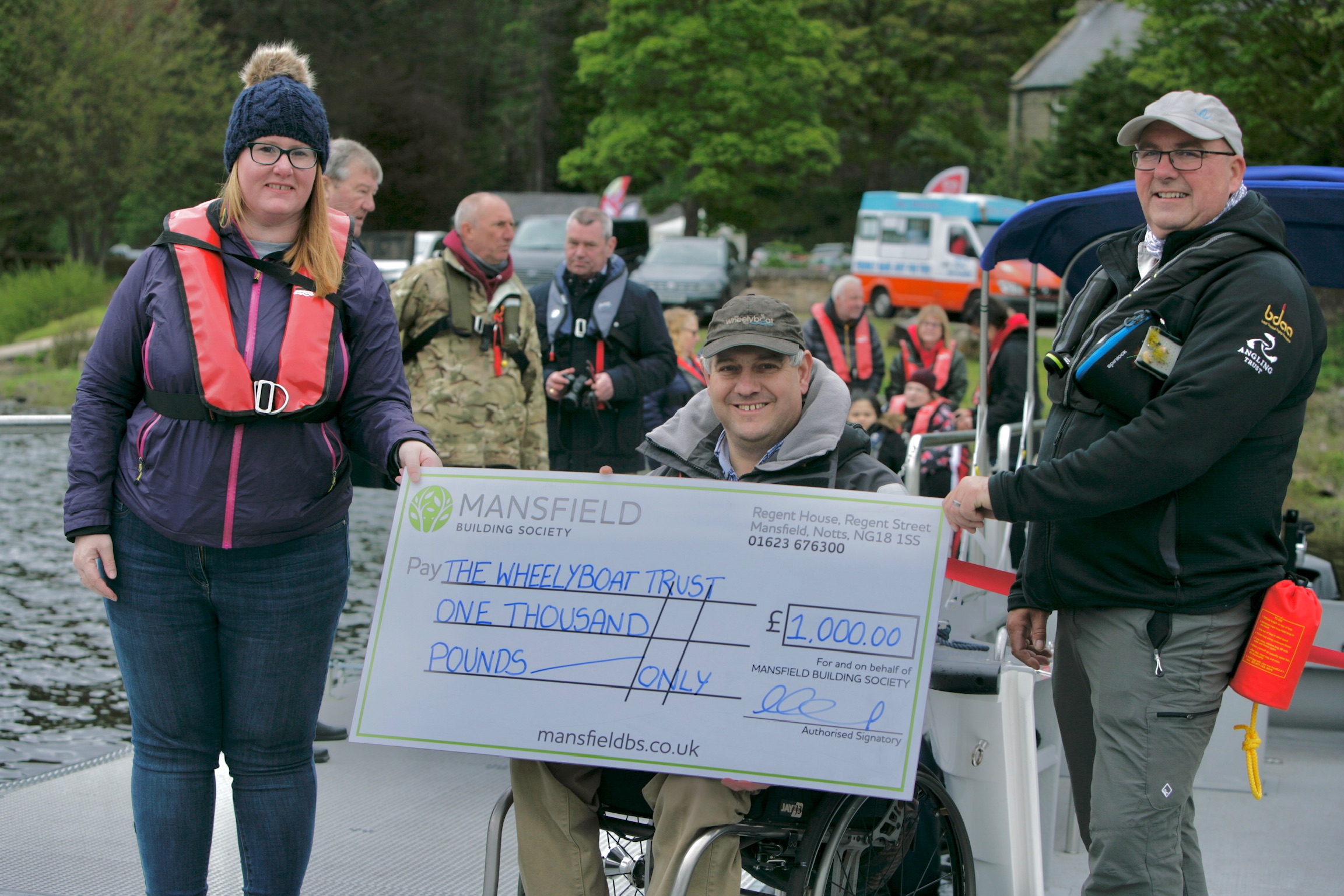 Man and woman and man in wheelchair holding mansfield bs cheque
