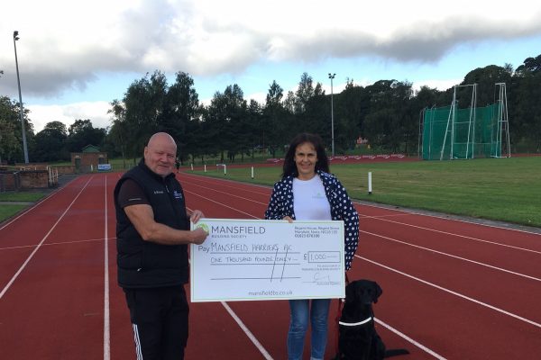 Dog man woman holding cheque on running track