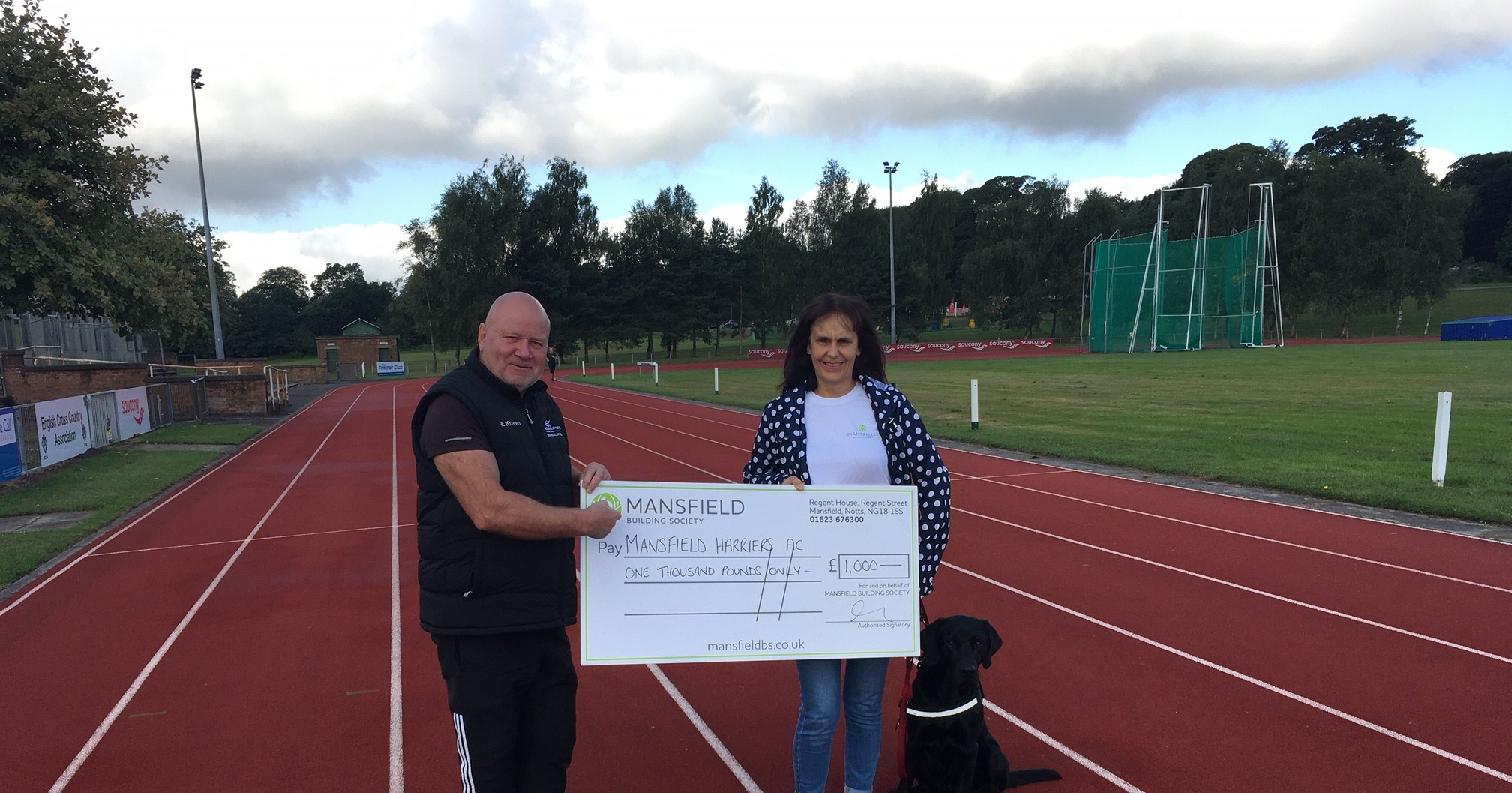 Dog man woman holding cheque on running track