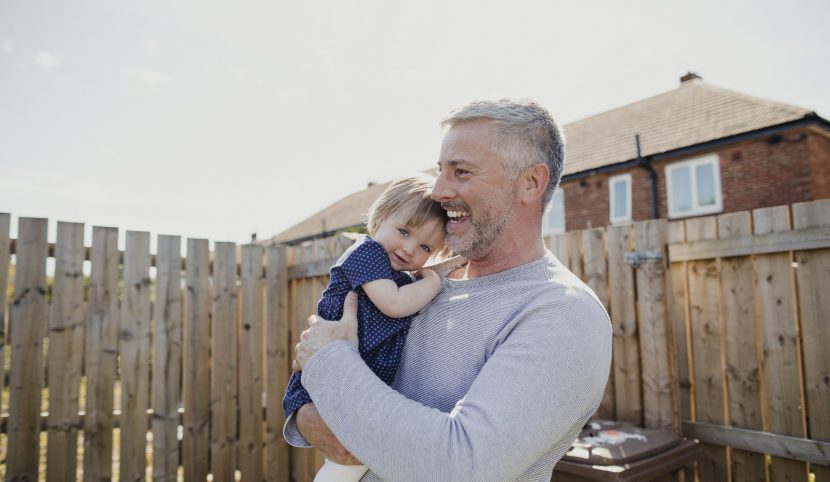 Smiling man holding young daughter