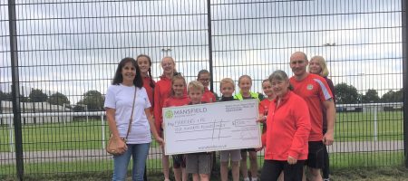 Children holding large cheque mansfield building society football pitch