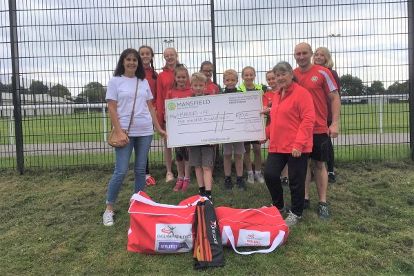 Children holding large cheque mansfield building society football pitch