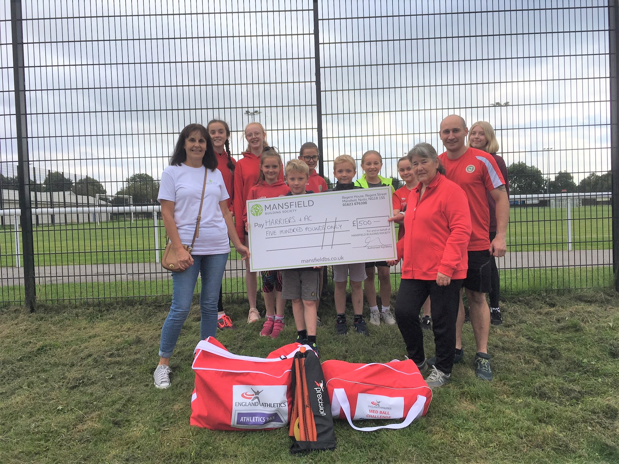 Children holding large cheque mansfield building society football pitch