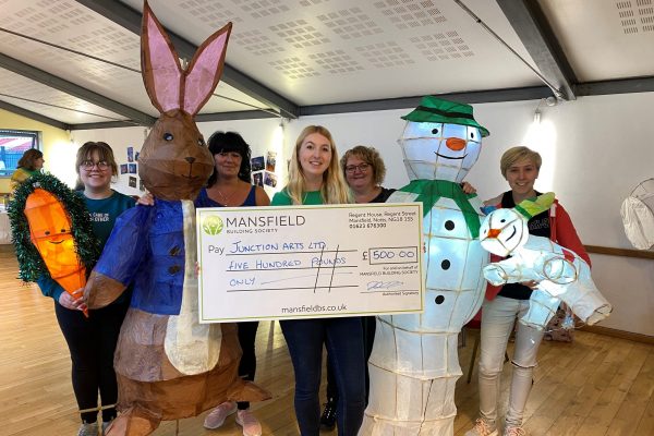Women holding bunny and snowman lanterns with large cheque