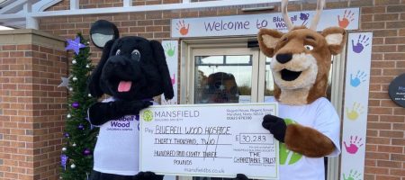 Dog and deer mascot holding cheque - mansfield bs bluebell wood hospice