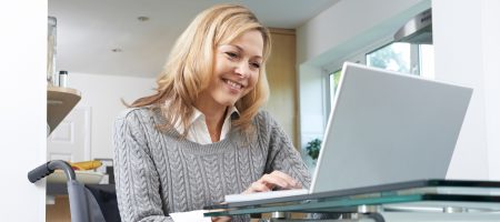 A disabled woman In her wheelchair using a laptop at home