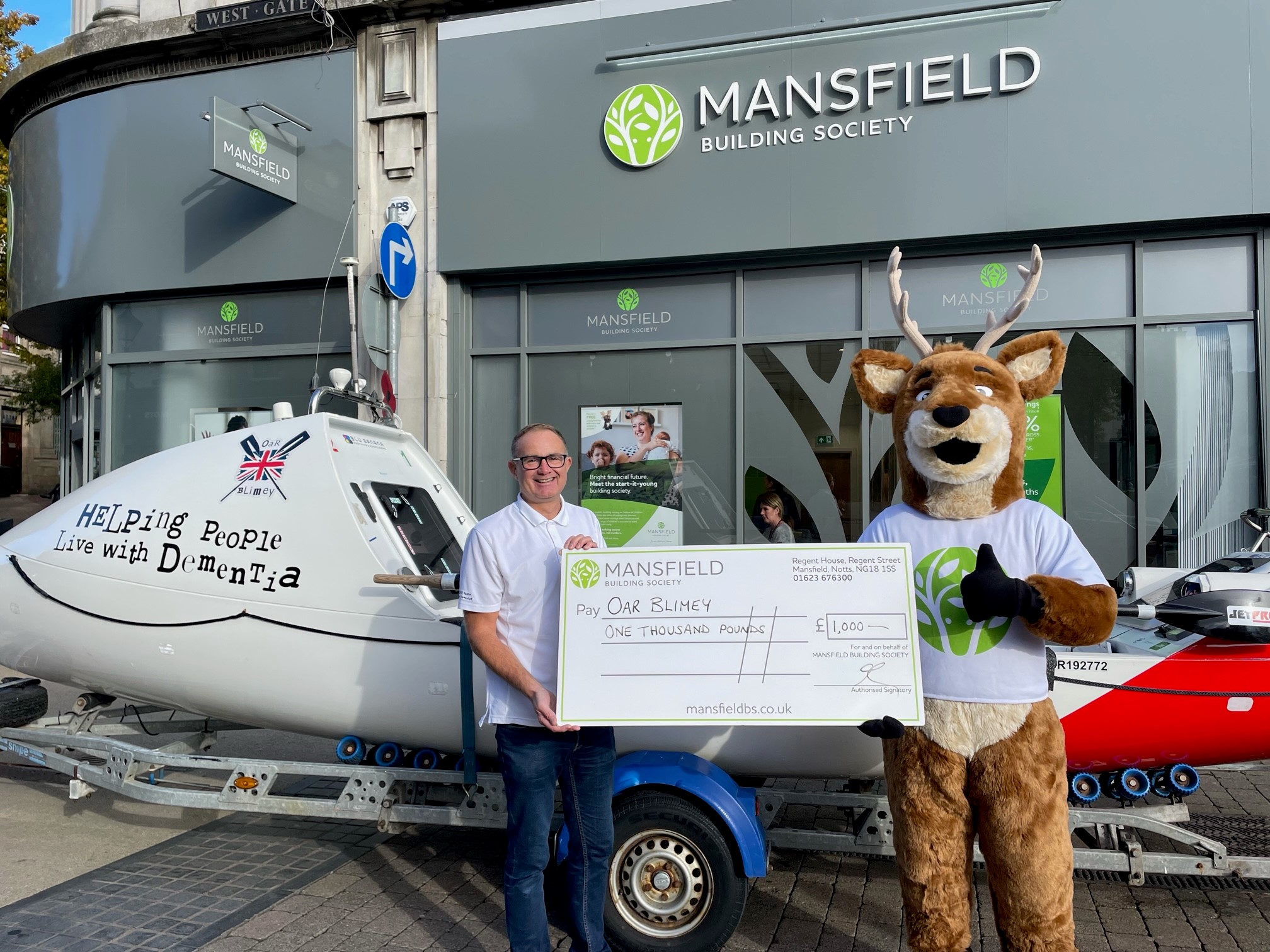 Stanley Stag cheque presentation with rowing boat outside a Mansfield Building Society branch