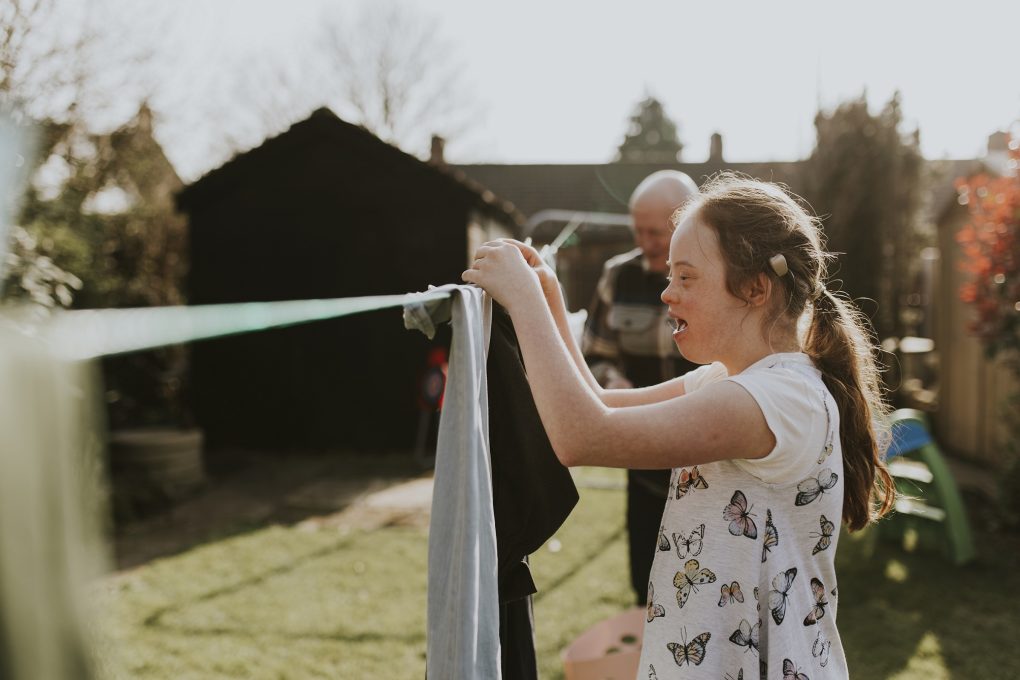 Down syndrome girl hanging washing