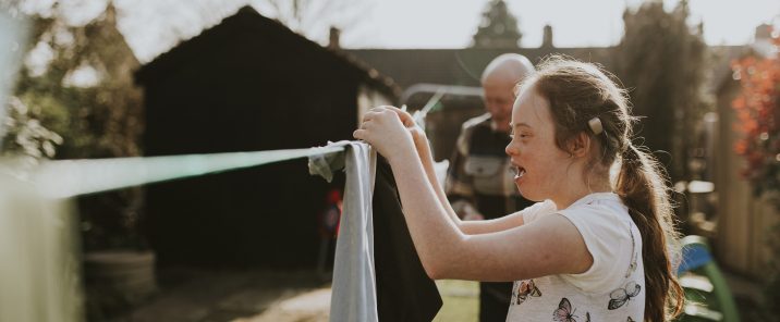 Down syndrome girl hanging washing